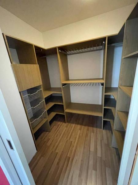 A wardrobe with wooden shelves and storage baskets in a 3-room apartment.