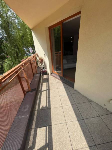 A balcony with tiles in a 3-room apartment with a view of the trees.