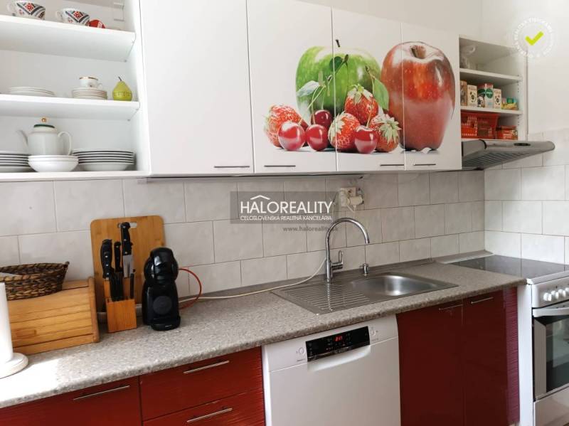 A kitchen in a 3-room apartment with white cabinets and a fruit motif on the doors.
