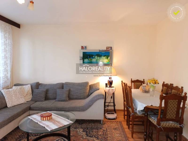 Living room in a three-room apartment with a large sofa and a wooden dining table.