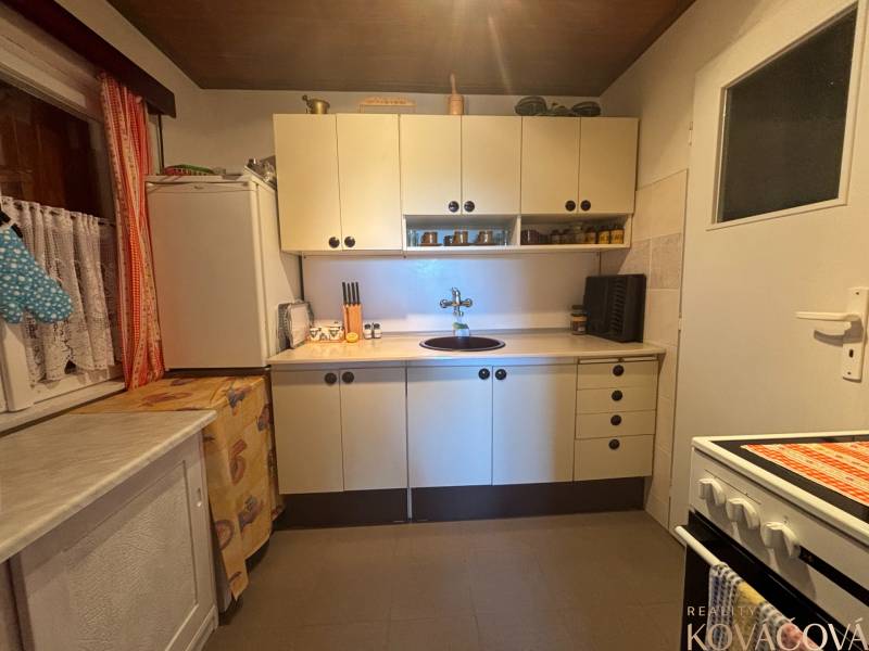 A cottage kitchen with white cabinets, a stove, and a sink.