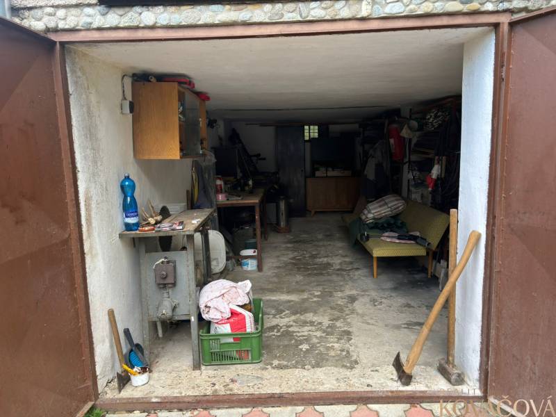 A garage with open doors, various tools, a loosely placed axe, in a country cottage.