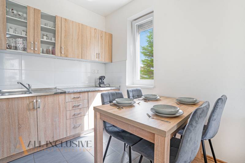A kitchen in a 2-room apartment with wooden cabinets and a dining table.