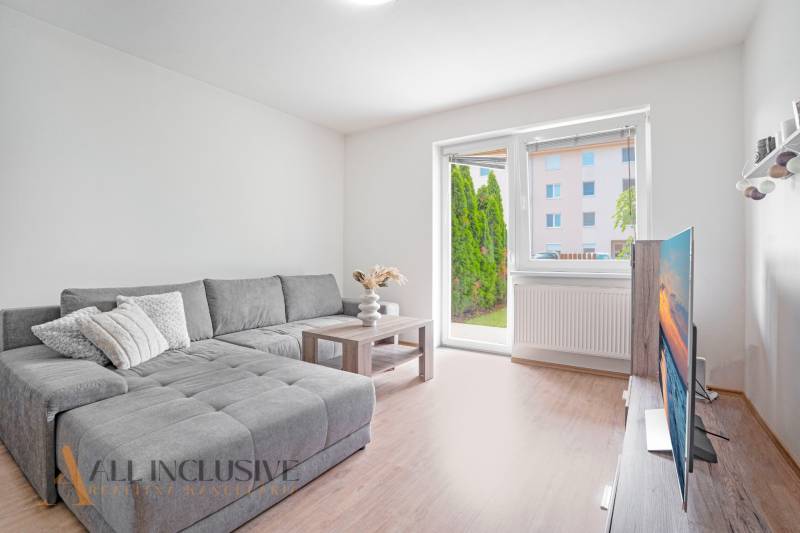 Living room with a corner sofa, television, and a view of the garden in a 2-room apartment.