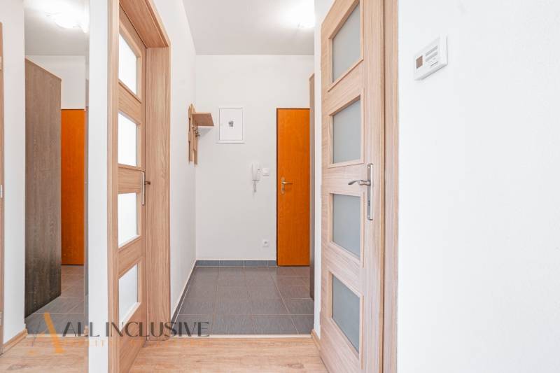 Entrance hallway in a 2-room apartment with wooden doors and tiles.