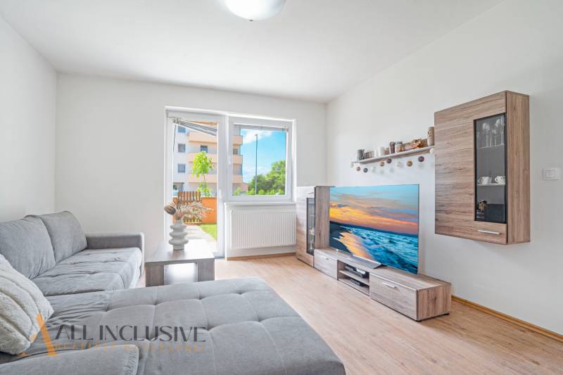 Living room in a two-room apartment with a sofa, television, and access to the terrace.