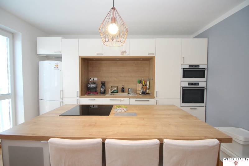 A kitchen in a 2-room apartment with built-in appliances and a bar counter.