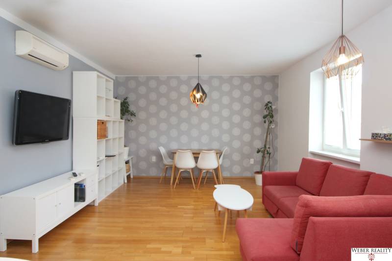 Living room in a 2-room apartment with a red sofa, dining table, and TV.