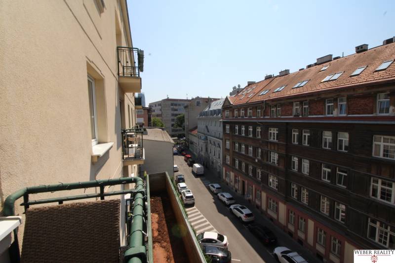 View from the balcony onto the street in Bratislava, Old Town, Medená, along a row of cars and buildings.