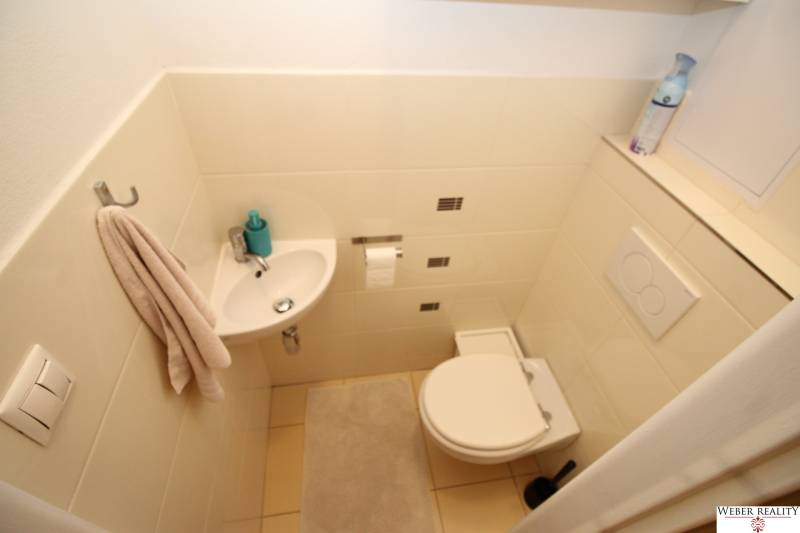 Compact bathroom with a sink, toilet, towel, and mat in a 2-room apartment.