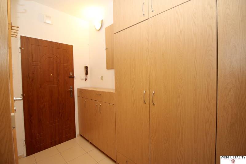 Entrance hallway in a 2-room apartment with wooden cabinets and tiles.