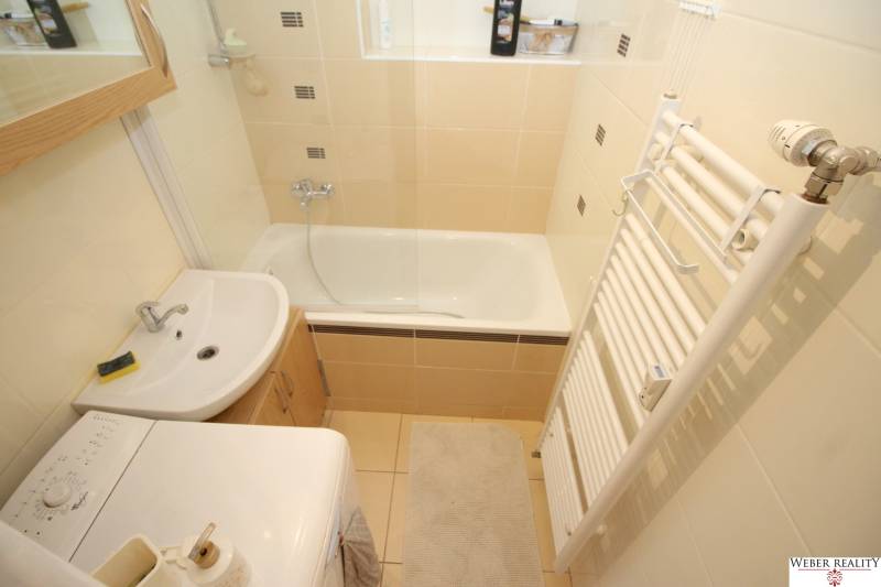 Compact bathroom with a bathtub, sink, and washing machine in a 2-room apartment.