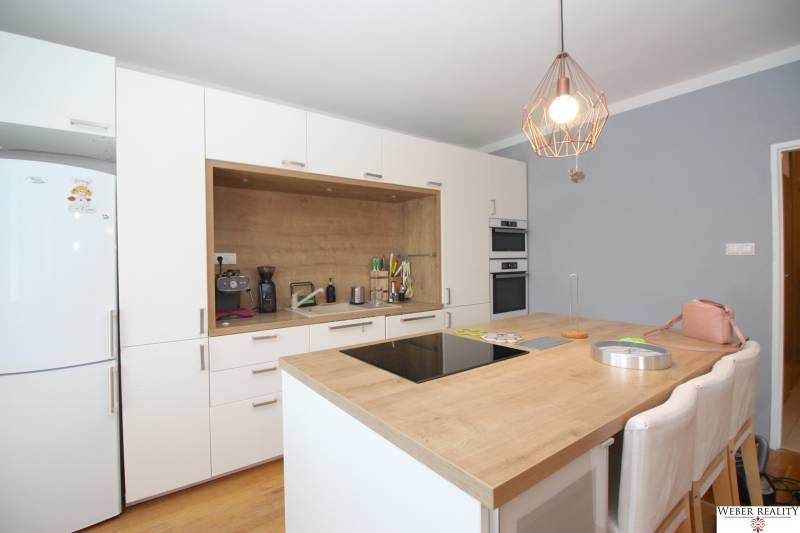 A kitchen with an island, pendant light, stove, and appliances in a two-room apartment.