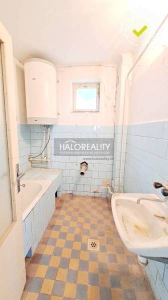 A bathroom in a family house with blue tiles, a bathtub, and a sink.