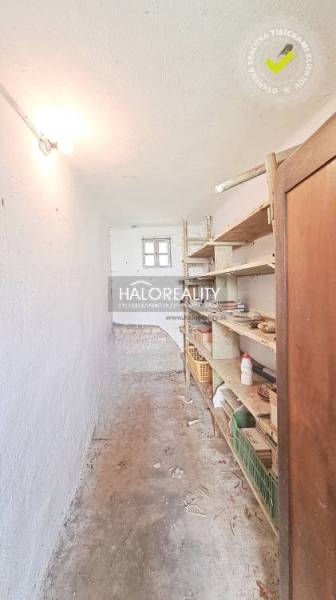 A narrow hallway with storage shelves in a family house in Norovce.