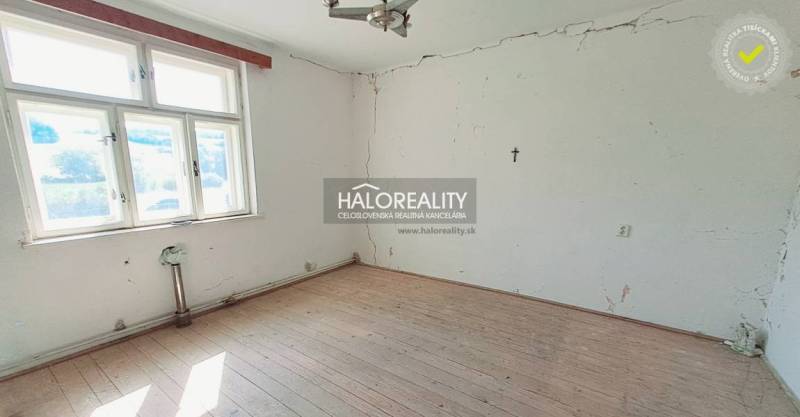 A room in a family house with a wooden floor and cracks on the walls.