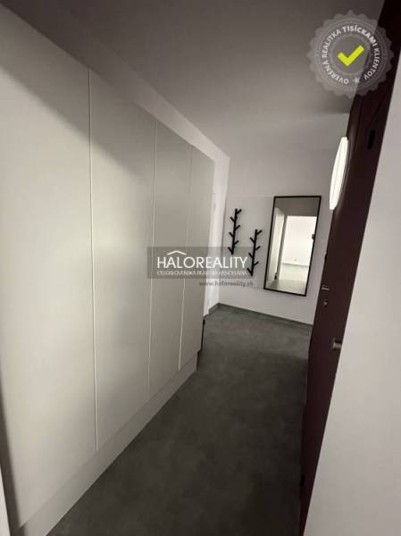 Purple kitchen unit and large wall clock in a studio apartment.