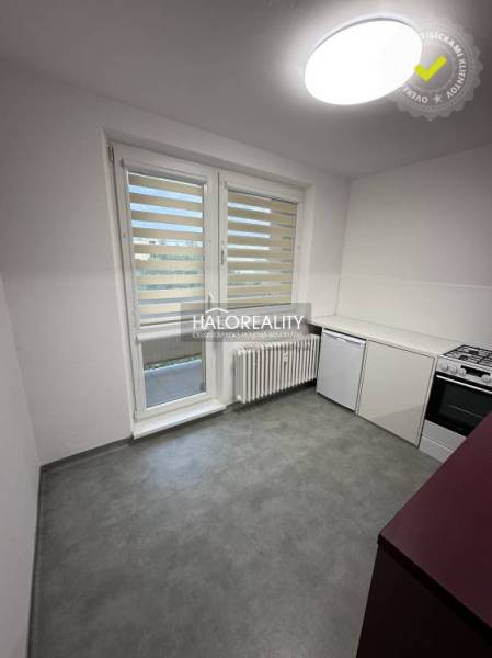 Kitchen area of a studio apartment with pink cabinets and a stove.