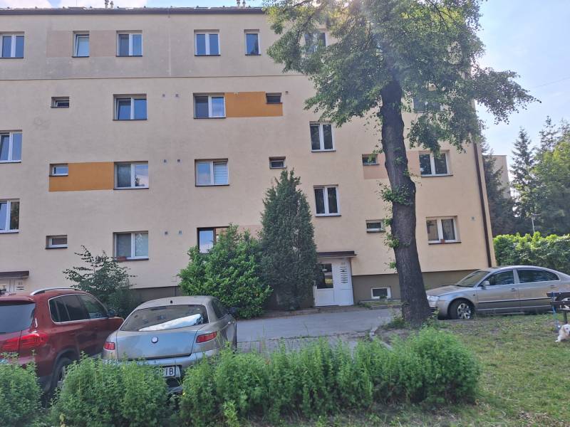 Apartment building in Prešov with parked cars and trees in front of a 4-room apartment.