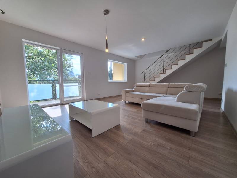A bright living room with a white sofa and a staircase in a 4-room apartment.