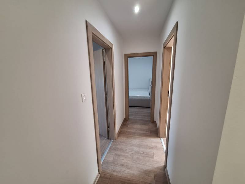 A hallway with wooden flooring and light-colored walls in a 4-room apartment.