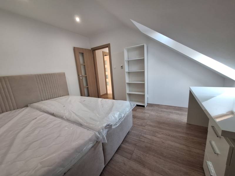 Bedroom in a 4-room apartment with a bed, shelf, and slanted ceiling.