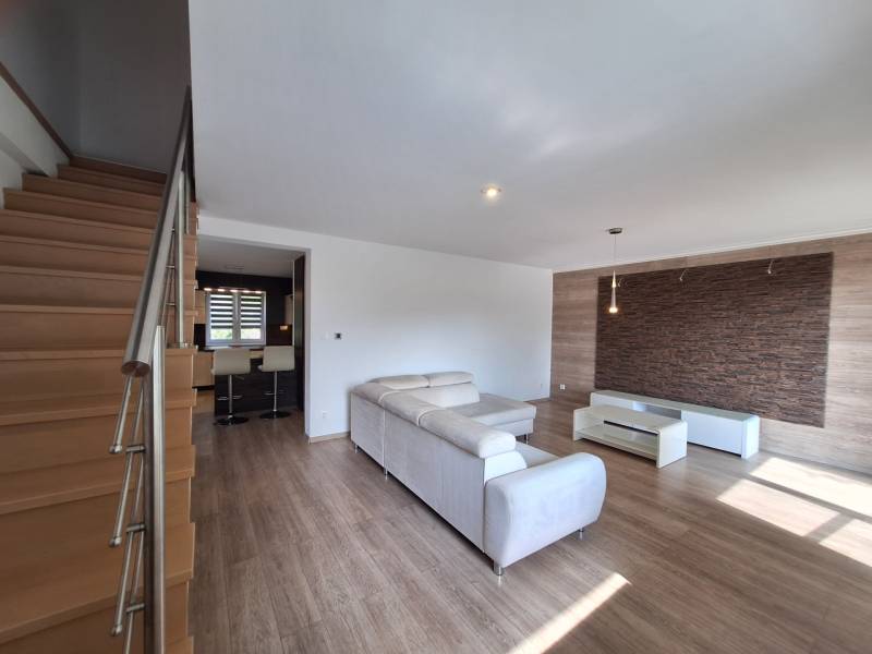 4-room apartment with a wooden staircase, white couch, and dark wall cladding.
