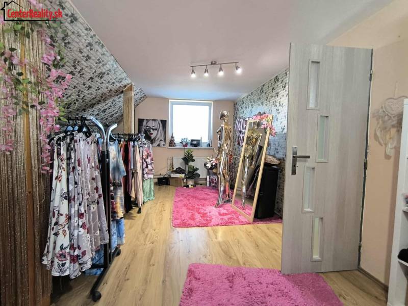 A dressing room in a family house with clothes hangers and a mirror on a pink carpet.