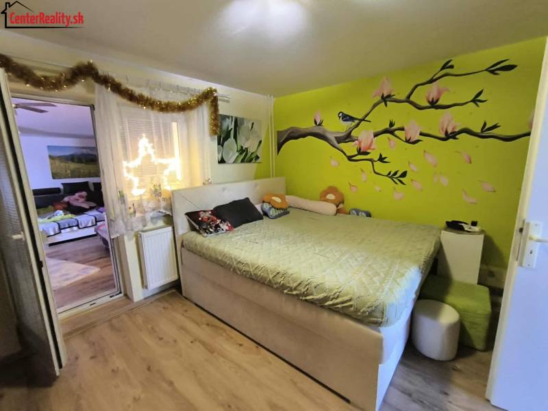 A bedroom in a family house with a colored wall and decoration, connected to the living room.