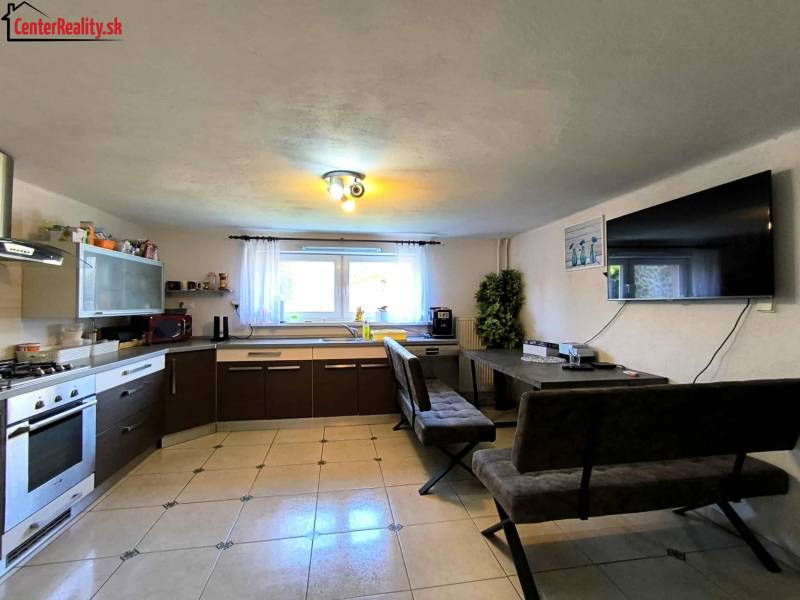 A kitchen with a kitchen unit, table, benches, and a television in a family house.