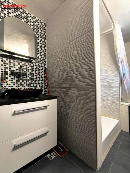 A bathroom with a tiled sink and shower in a family house.