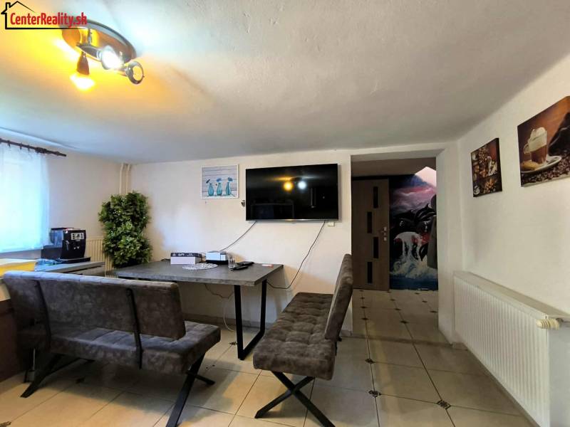 Dining room in a family house with a television, sofas, and interior decorations.