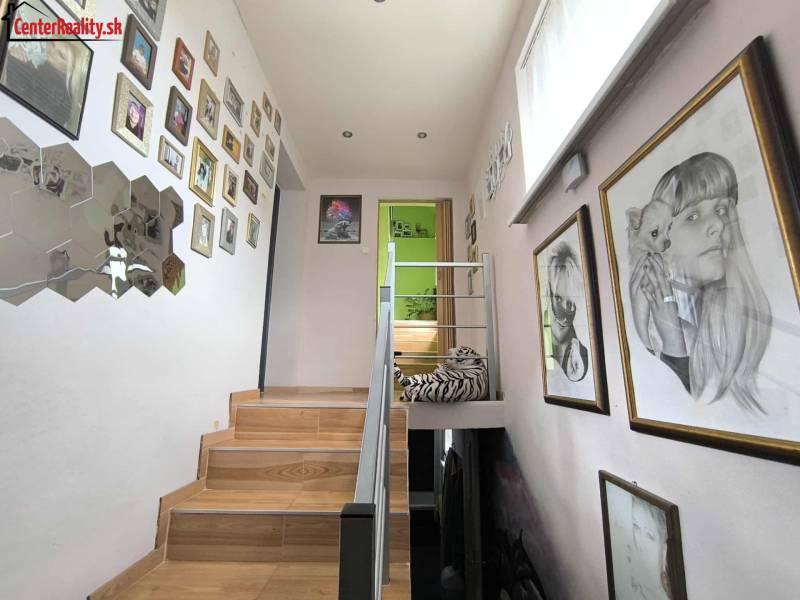 A staircase in a family house with many paintings on the walls.