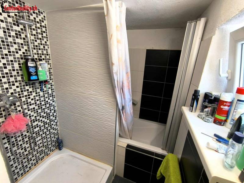 A bathroom in a family house with a modern shower tray and mosaic tiles.