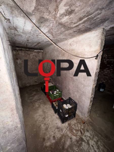 The basement of a family house with stored preserves and crates, part of a real estate agency's offer.