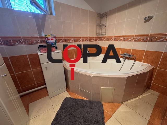 A bathroom in a family house with a corner bathtub and orange tiles.