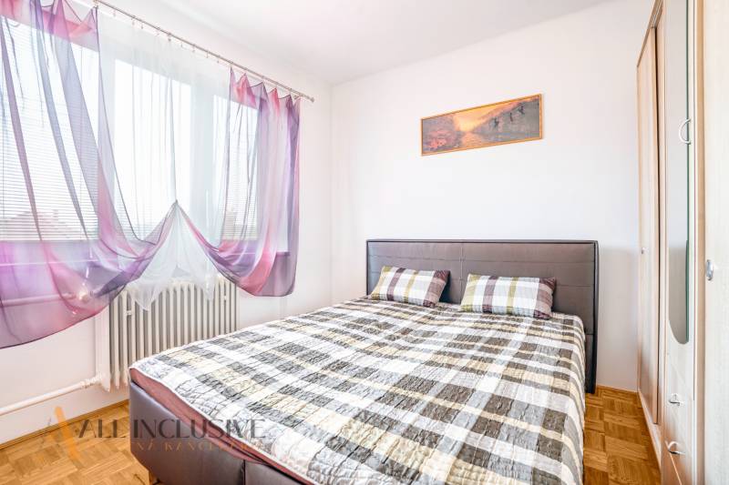 A bedroom in a family house with a bed, curtains, and a built-in wardrobe.