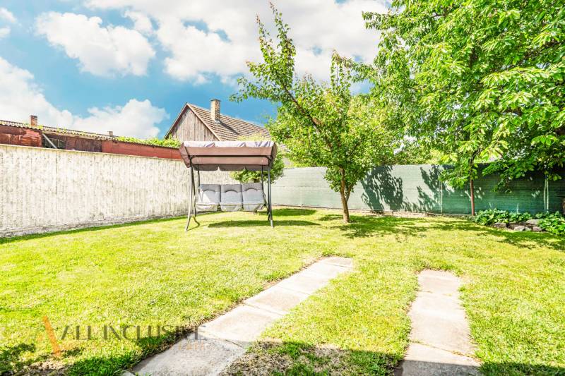 A garden in a family house in Sapa with a swing and trees, surrounded by a fence.