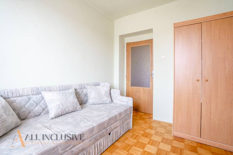 A room with a sofa, a wooden wardrobe, and a floor in a family house.