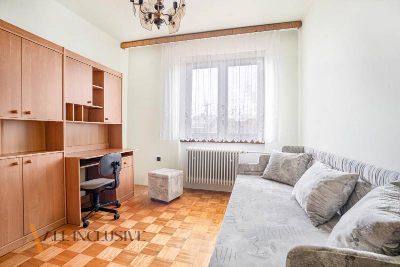 A room with a desk, sofa, and wooden furniture in a family house.