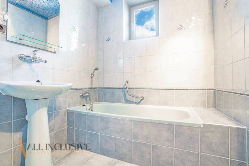 Tiled bathroom with a bathtub and a sink in a family house.