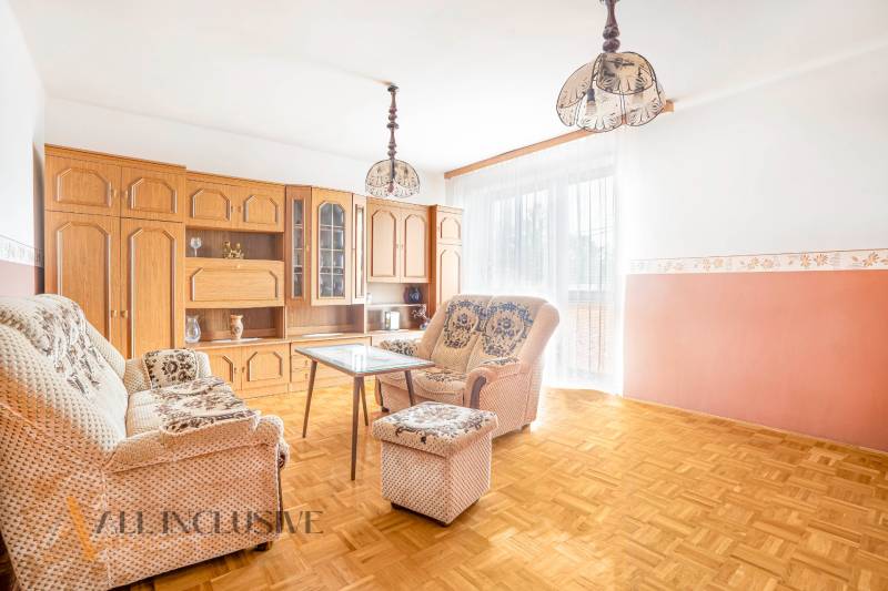 Living room with comfortable seating, a coffee table, and a wooden wall unit in a family house.