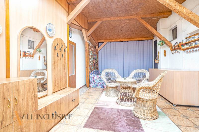 Interior of a family house with chairs, a table, and wooden paneling.