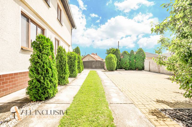 A family house in the town of Sap with a driveway lined with green shrubs.