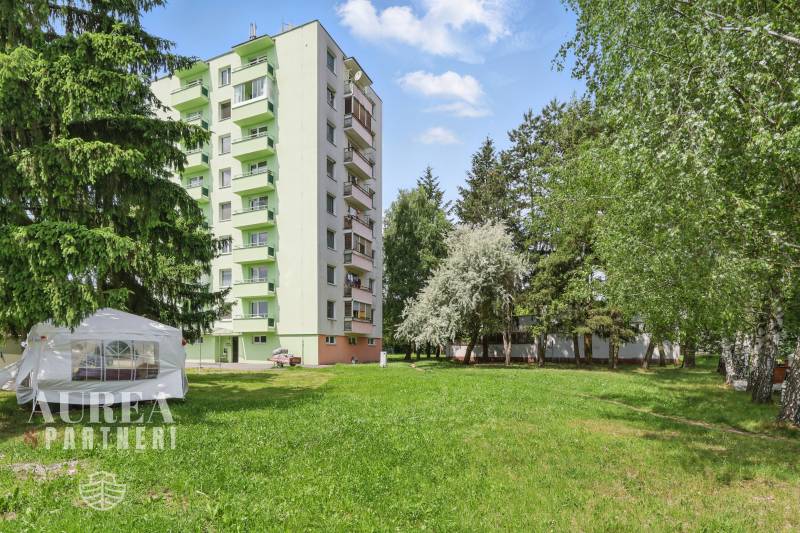 An apartment building with green balconies, surrounded by trees on Slnečná Street in Kováčová. Plots - residential.