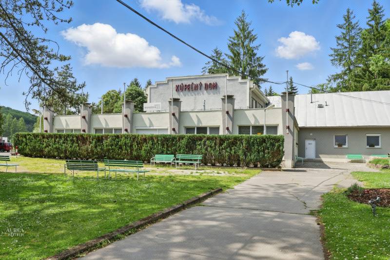 The building of the spa house on Slnečná Street in Kováčová, surrounded by greenery and benches.