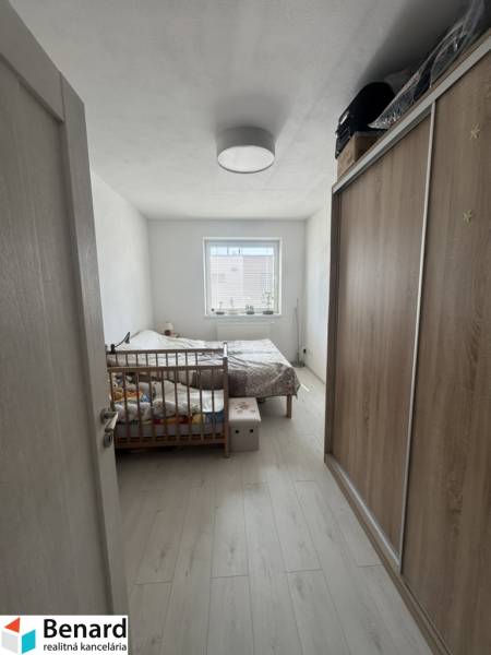 Bedroom in a 2-room apartment with a wooden bed, wardrobe, and window with daylight.