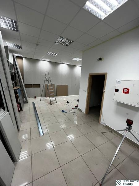 Interior of commercial premises with a ladder, tiles, and lighting during renovation.