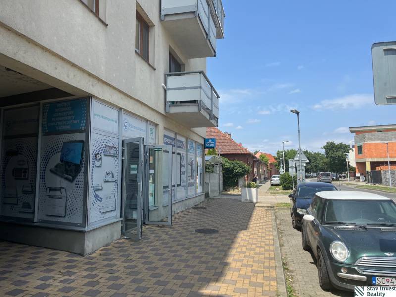 A building with commercial spaces on Štúrova Street in Senec, next to parked cars.