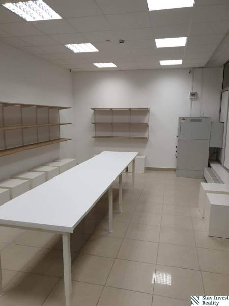 White table, shelves, tiles, commercial spaces with lighting and installed ceiling panels.